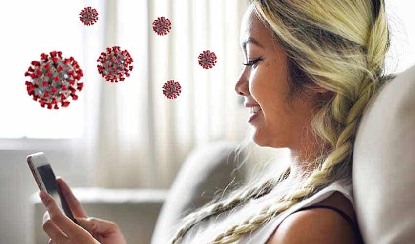 A woman looking at her cell phone with coronavirus in the air