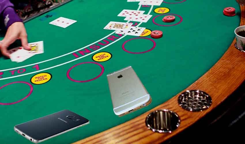 An iPhone and a Samsung Android device tossed onto a blackjack table like cards