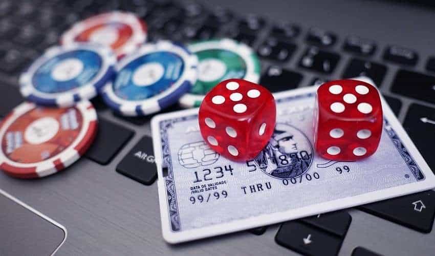 a laptop computer with a credit card, dice, and poker chips atop the keyboard