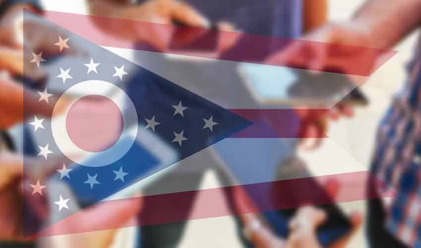 real money sports gambling apps in Ohio for 2023 men gambling on sports using their smartphones with an image of the Ohio state flag overlayed